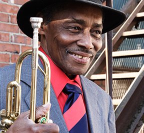 African American musician holding a trumpet smiling. 