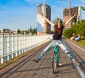 Happy girl riding a bike on a waterfront trail.