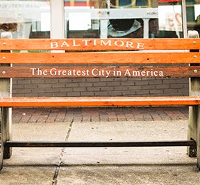 Wood and cement bench with "Baltimore: The Greatest City in America" written on the boards.