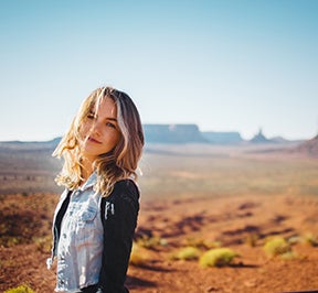 Pretty, young woman posing in front of a picture perfect desert landscape. 
