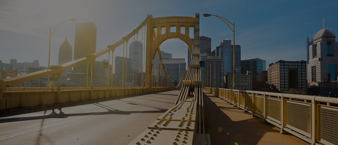 Bright sunrise over a Pittsburgh bridge and downtown skyline.