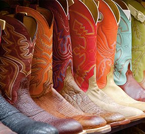 Colorful cowboy boots sitting on a retail shelf. 