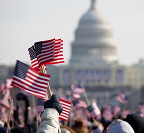 People waving flags in front of the Washington Capital building.