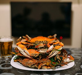 Crab piled high on a plate with a beer.